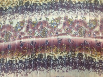 Soepele stof, iets gerimpeld, met bloemenranden in tinten oker en aubergine. Mooi voor wijdere rok of tuniek/blouse. 